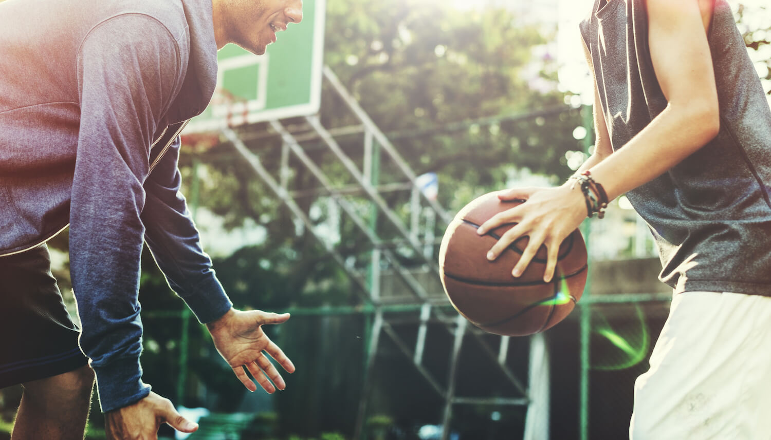 Zdrowy i aktywny styl życia. Dwaj mężczyzni grają w koszykówkę. Mężczyzna po prawej stronie trzyma w rękach piłkę.